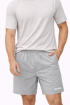 Man wearing a light gray t-shirt and shorts on a white background